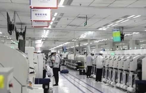 图片展示的是联宝（合肥）电子科技有限公司的生产车间。画面中，工人们身着白色工作服，戴着帽子，正在操作或检查设备。车间内设备整齐排列，地面干净整洁，天花板上装有照明灯和空调。墙上有标识牌，显示“锡膏检测机”等字样。该图片与上下文紧密相关，直观呈现了合肥在产业投资中通过国有资本参与，为社会资本提供信心，最终实现国有资本良性循环的成果。